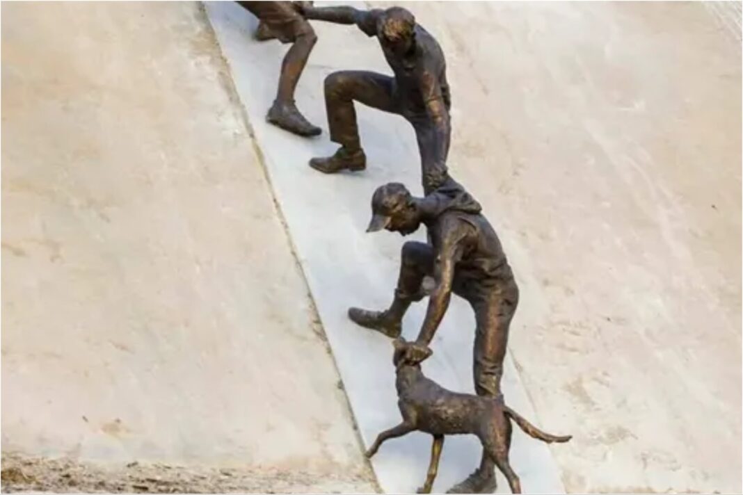 Estatua de figuras humanas formando una cadena para rescatar a un hombre y un perro, instalada sobre un río en Almatý, Kazajistán.