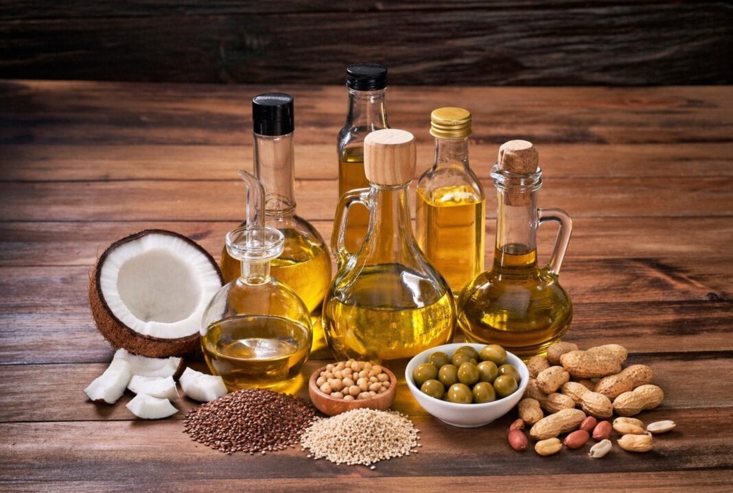 Botellas y frascos de distintos aceites saludables, como oliva, coco y girasol, sobre una mesa de cocina.