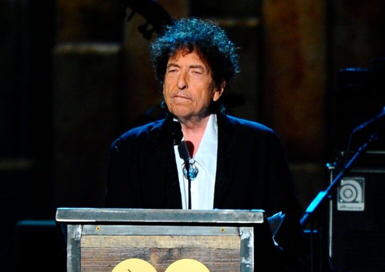 Bob Dylan en un escenario, con guitarra acústica, durante un concierto en los años 60