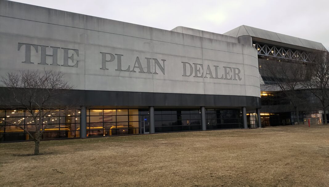 Redacción de un periódico con un periodista trabajando en una computadora y un símbolo de inteligencia artificial superpuesto