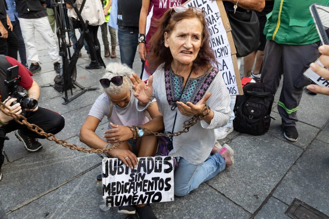 Dos mujeres jubiladas sentadas en el suelo durante una protesta pacífica.