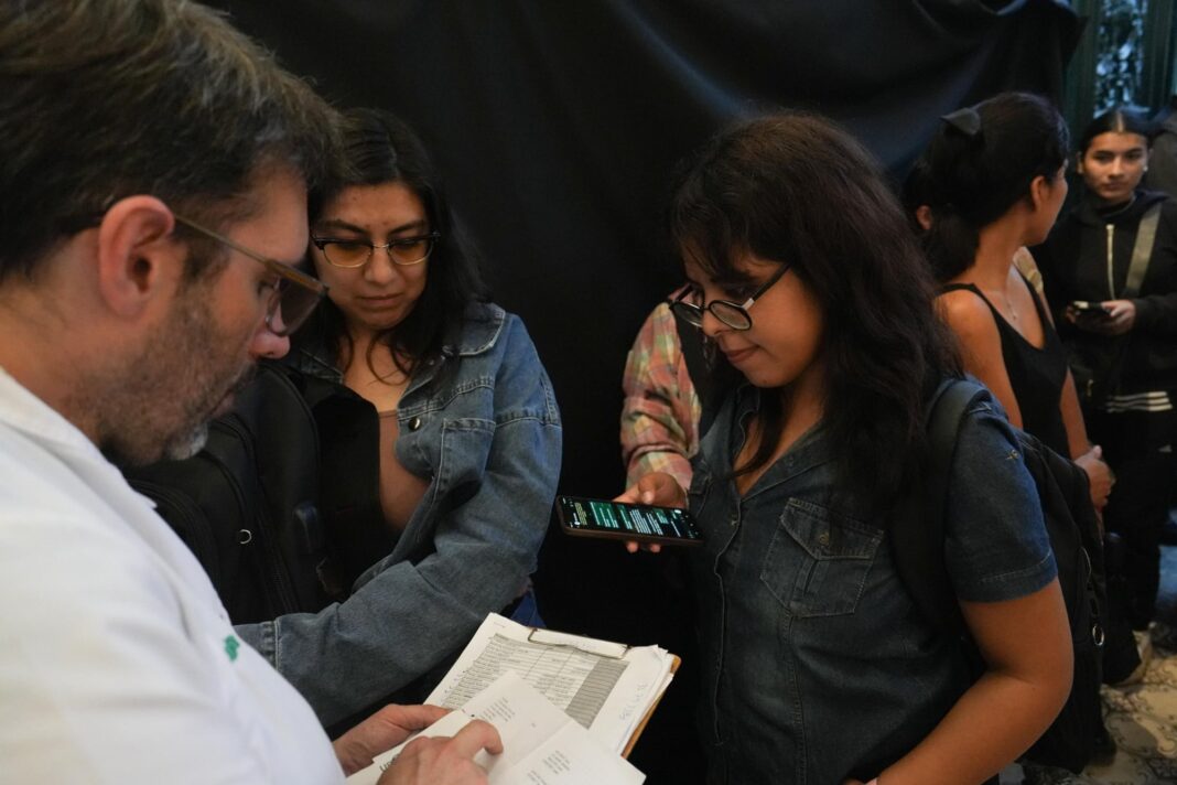 Estudiantes conversando en el patio de una facultad, con carteles de fondo.
