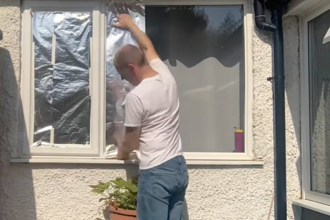 Ventana cubierta con papel aluminio para reflejar el calor del sol en un día caluroso.