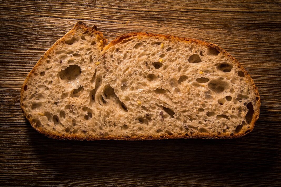Rebanada de pan de masa madre artesanal sobre una tabla de madera.