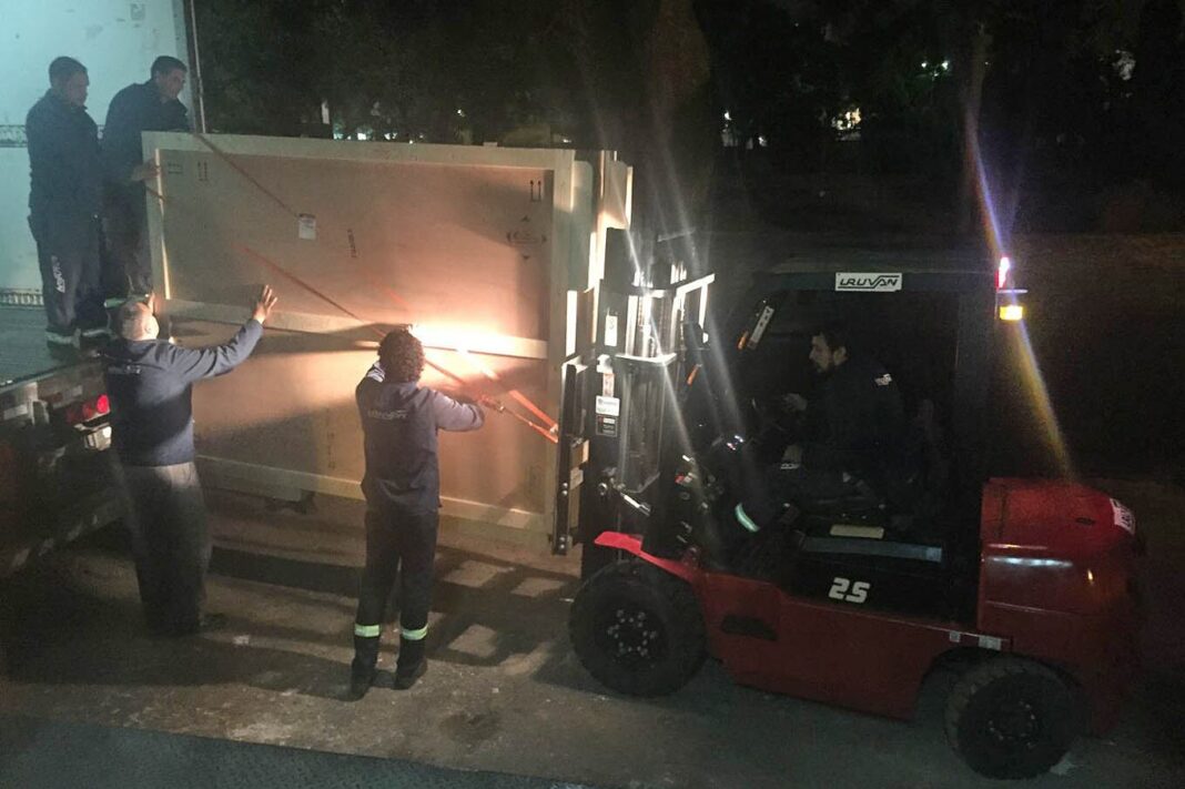 Profesionales supervisando el embalaje y traslado de una pintura en un museo.