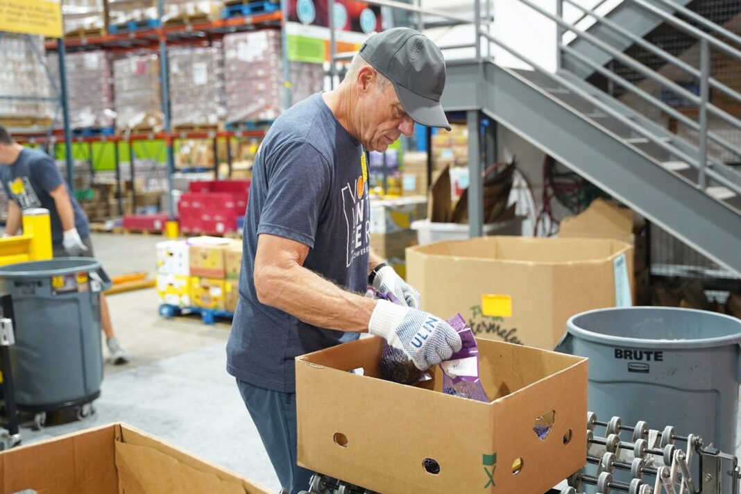 Trabajador agrícola revisando caja de alimentos provista por programa de asistencia gubernamental.
