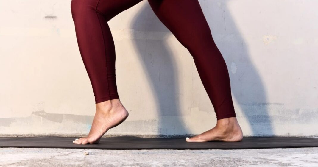 Persona haciendo ejercicio de estiramiento de pie con una pelota bajo el arco plantar