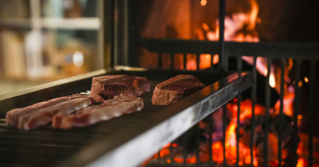 Persona frotando un diente de ajo en una parrilla caliente antes de colocar la carne.