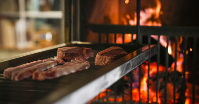 Persona frotando un diente de ajo en una parrilla caliente antes de colocar la carne.