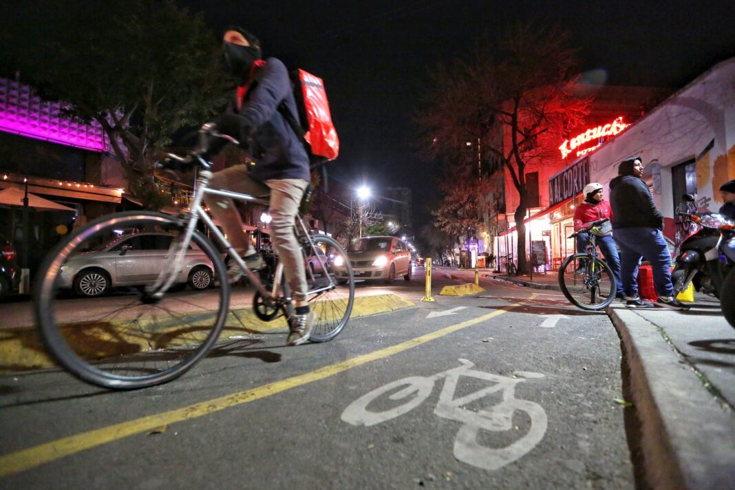 Repartidor de delivery en bicicleta con mochila térmica en una calle de Buenos Aires