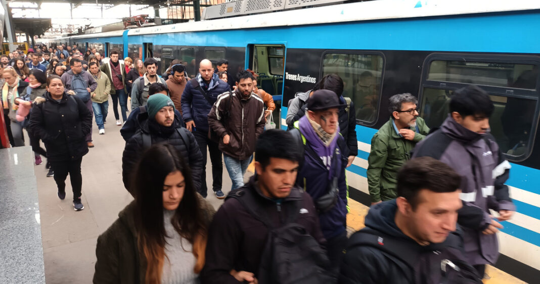 Colectivo y tren en el AMBA con cartel de aumento de tarifas