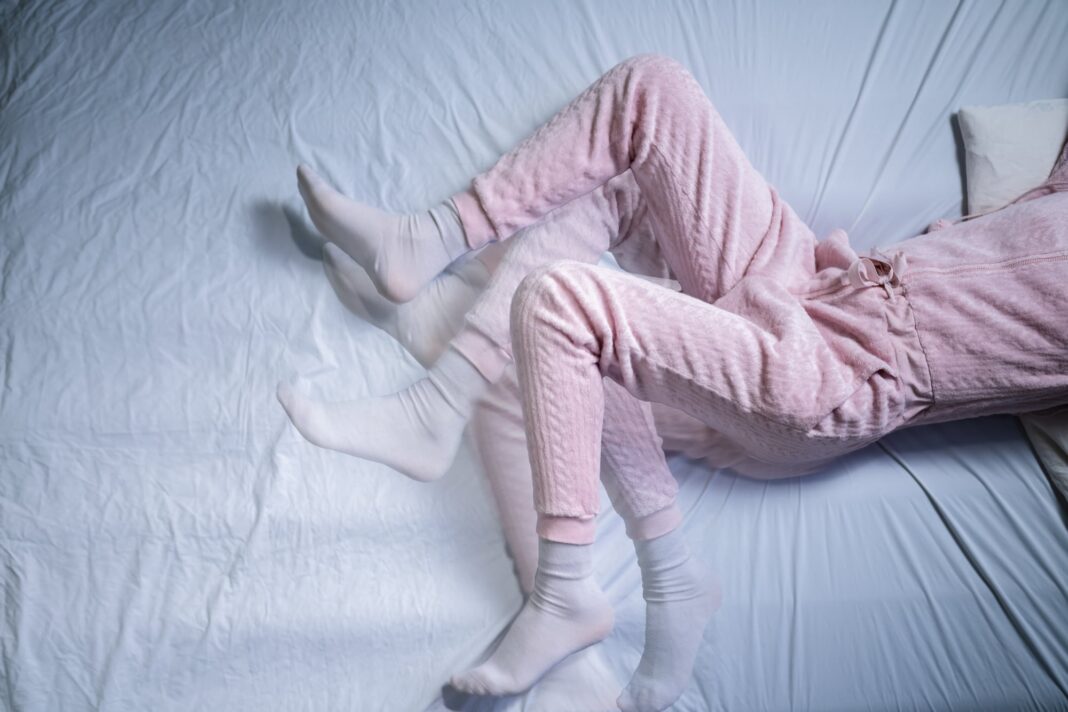 Persona sentada con molestias en las piernas por síndrome de piernas inquietas