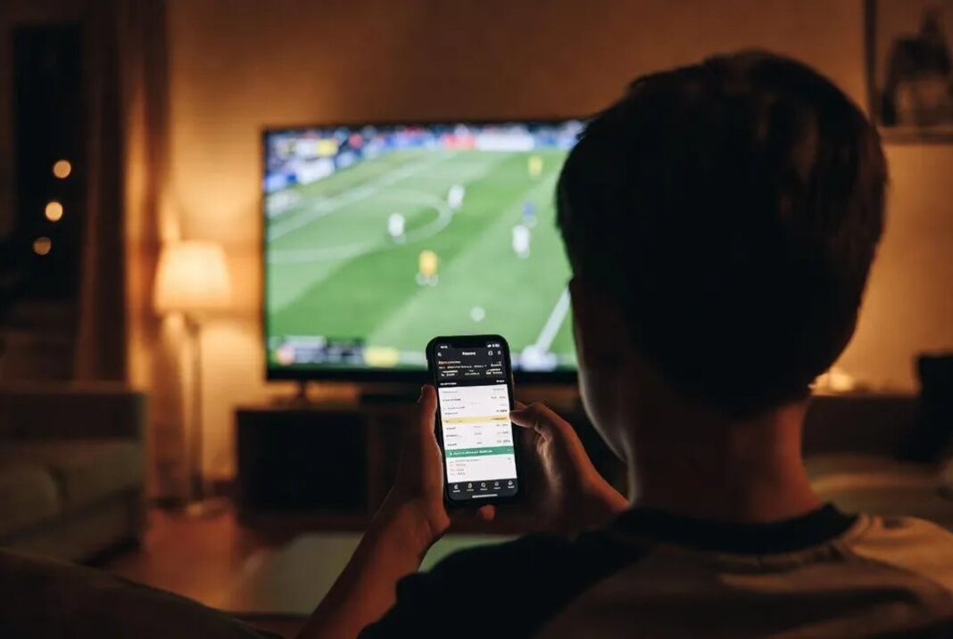 Adolescentes mirando un partido de fútbol con celulares en mano