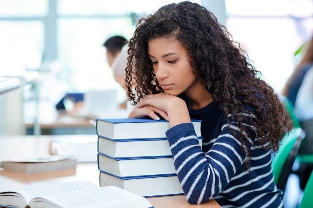 Estudiante universitario sentado en una biblioteca con expresión concentrada