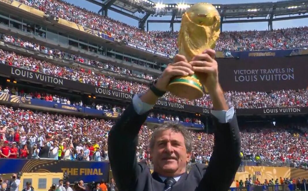 Mario Kempes y Andrés Iniesta sosteniendo la Copa del Mundo en el MetLife Stadium