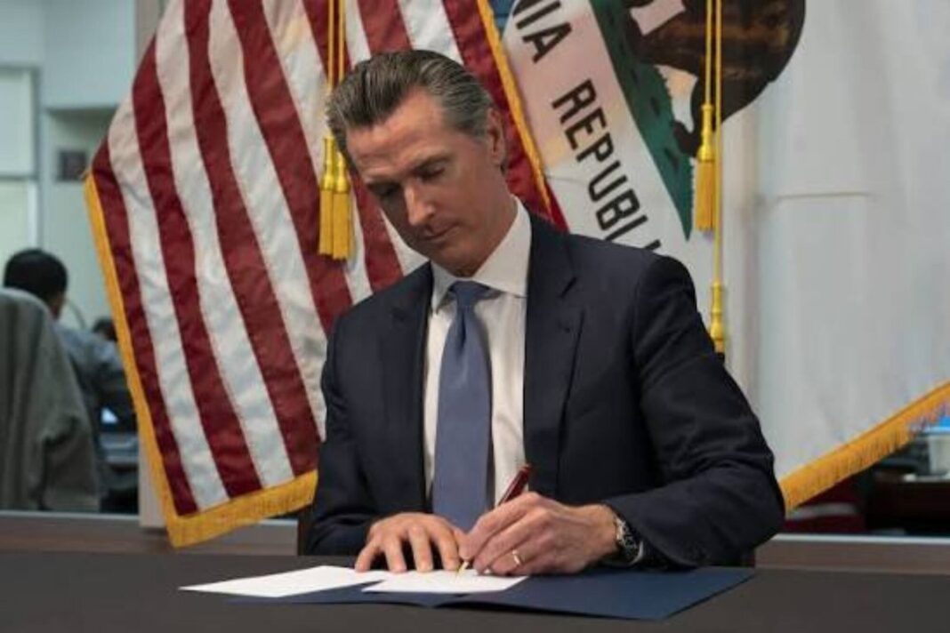 Gavin Newsom firmando documentos en su despacho