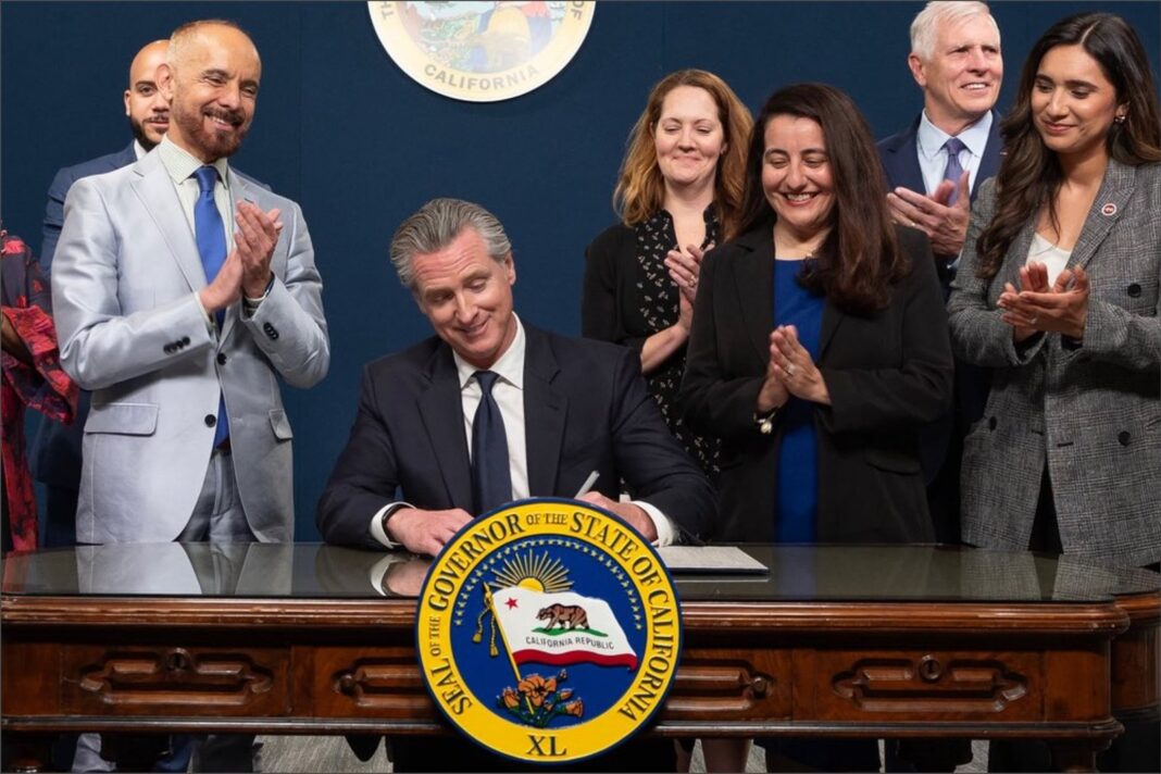 Gavin Newsom firma documentos en su oficina