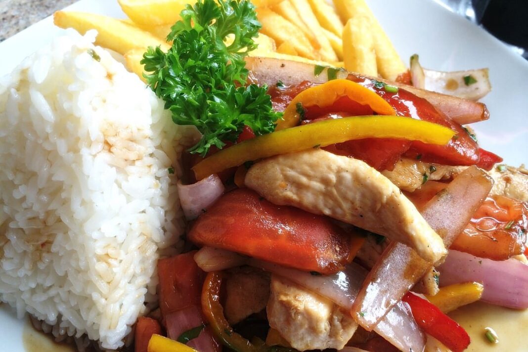 Saltado de pollo servido con arroz y papas fritas