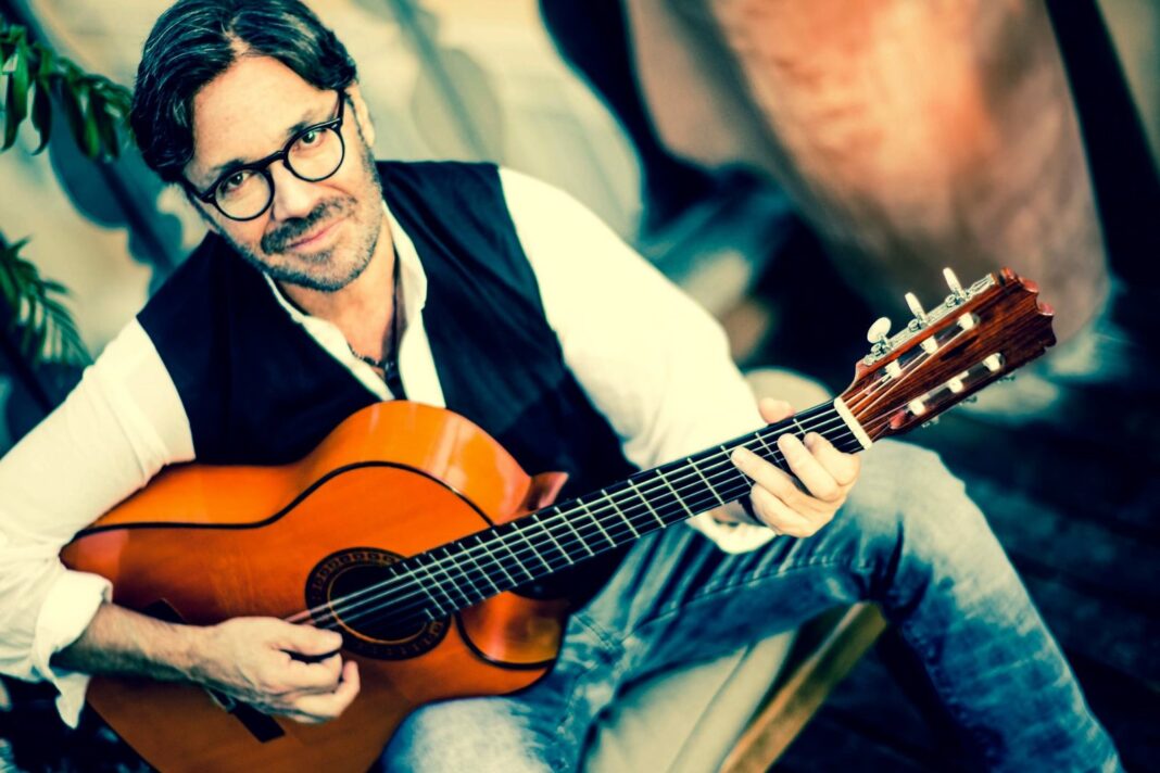 Al Di Meola tocando la guitarra en un escenario