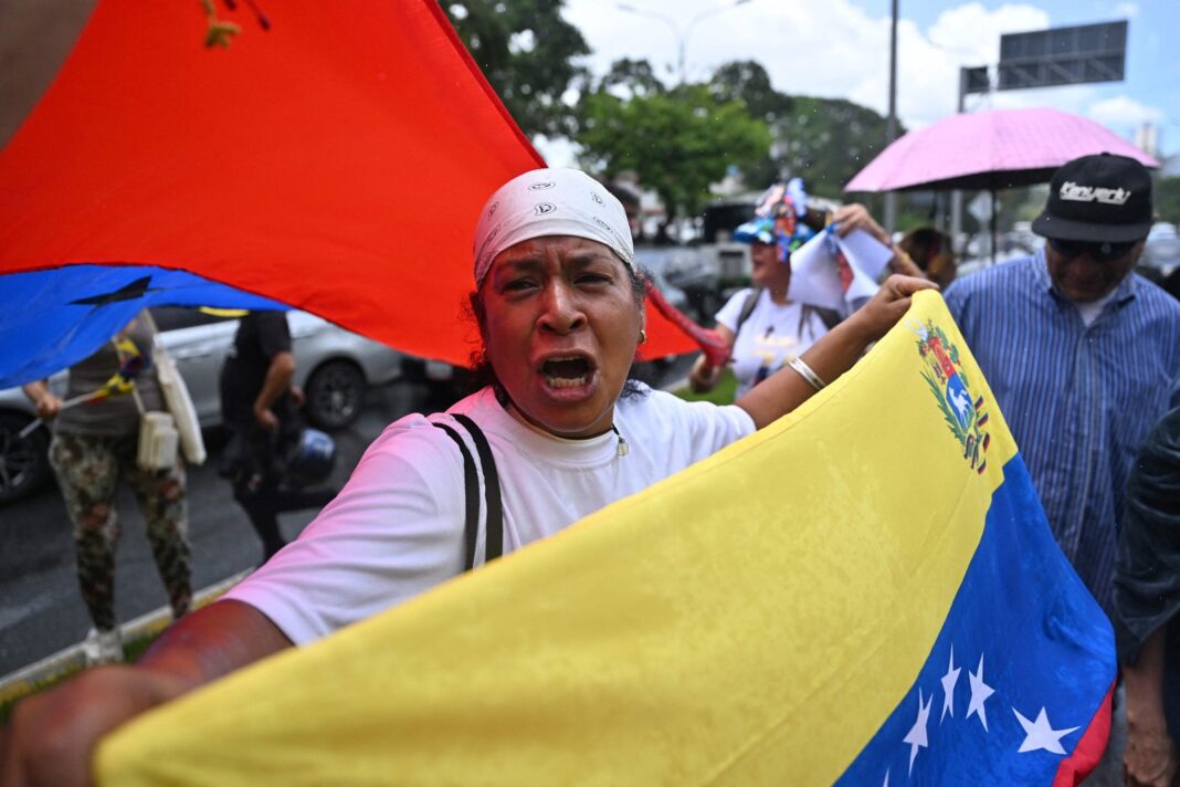 Caravana de vehículos y motocicletas con banderas venezolanas en una avenida