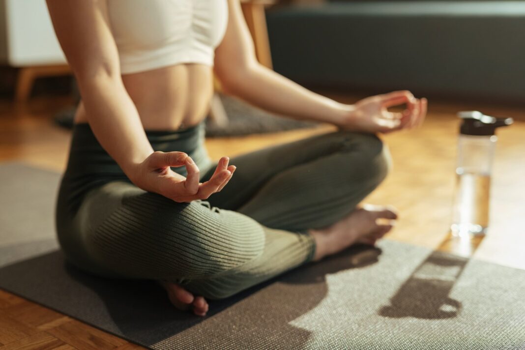 Persona practicando yin yoga en un mat, con luz tenue