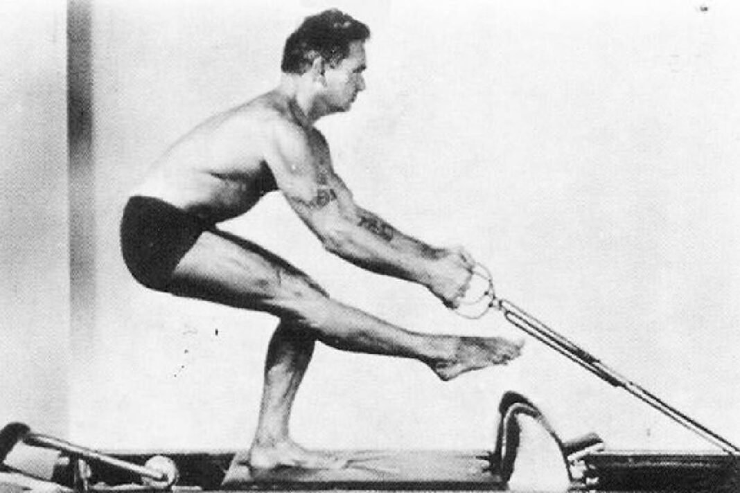 Instructora de pilates junto a una cama reformer en un centro de entrenamiento