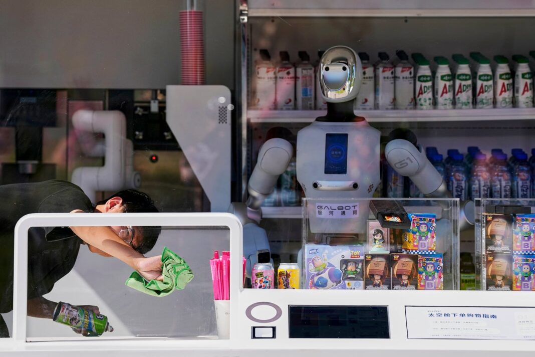 Robot Galbot en una tienda de bebidas en Pekín junto a un joven que limpia el vidrio